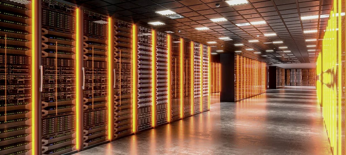 Rows of server racks lit in amber along a long, bright data-hall aisle