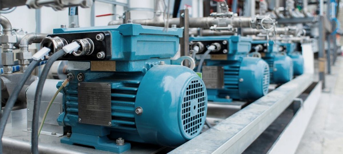 A row of blue electric motors on a process line, cable glands and stainless pipework around them
