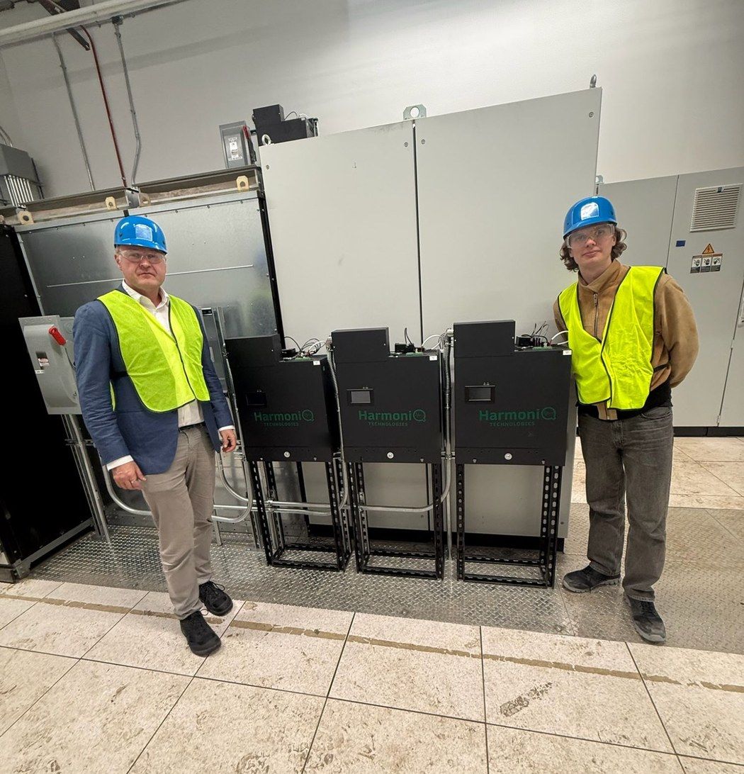 Two of the HarmoniQ team in hard hats and high-visibility vests either side of three installed HarmoniQ Deltas