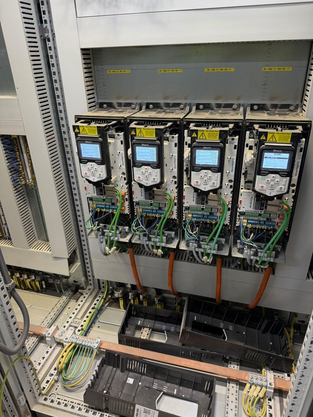 Variable speed drives mounted in an open motor control cabinet, their wiring below
