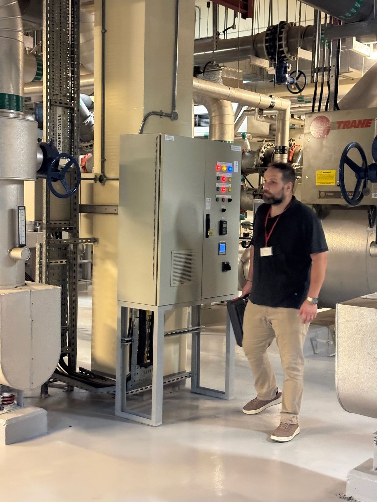 One of the team walking past a control panel among a hotel’s chillers