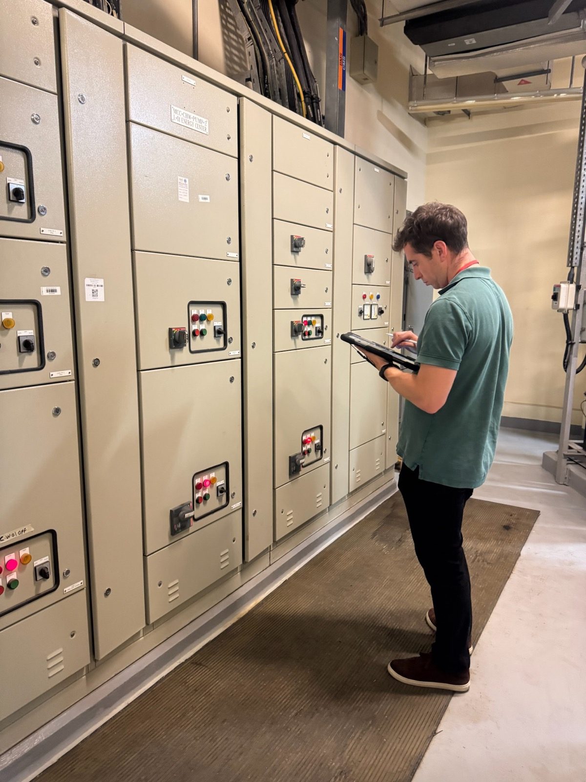 A HarmoniQ engineer recording readings on a tablet beside a hotel’s motor control centre