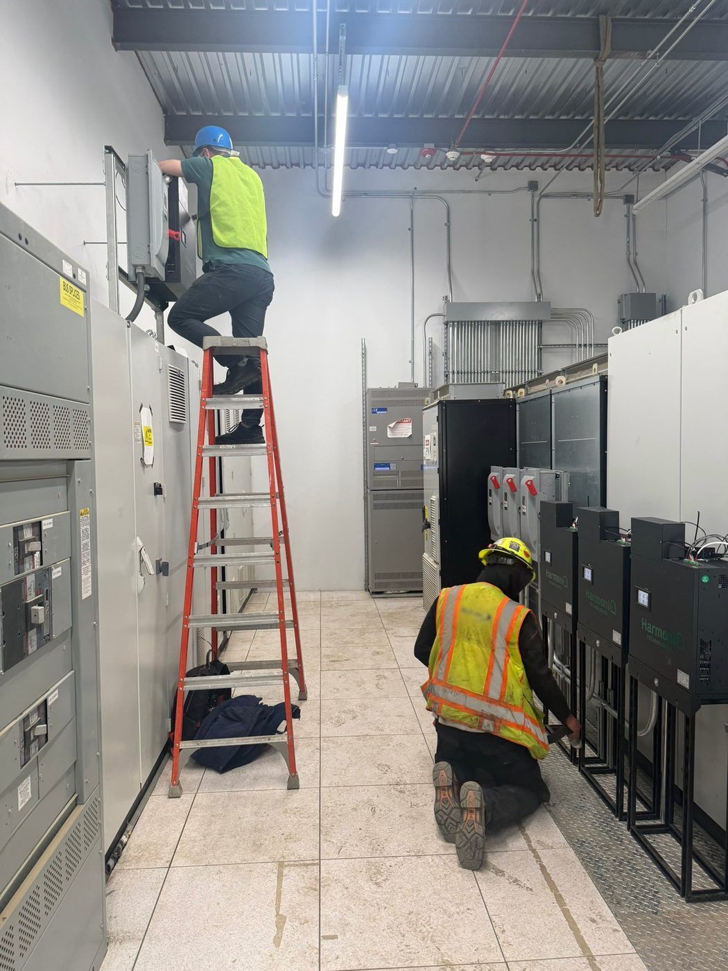 An installation crew in high-visibility vests wiring a row of Deltas in a switchroom