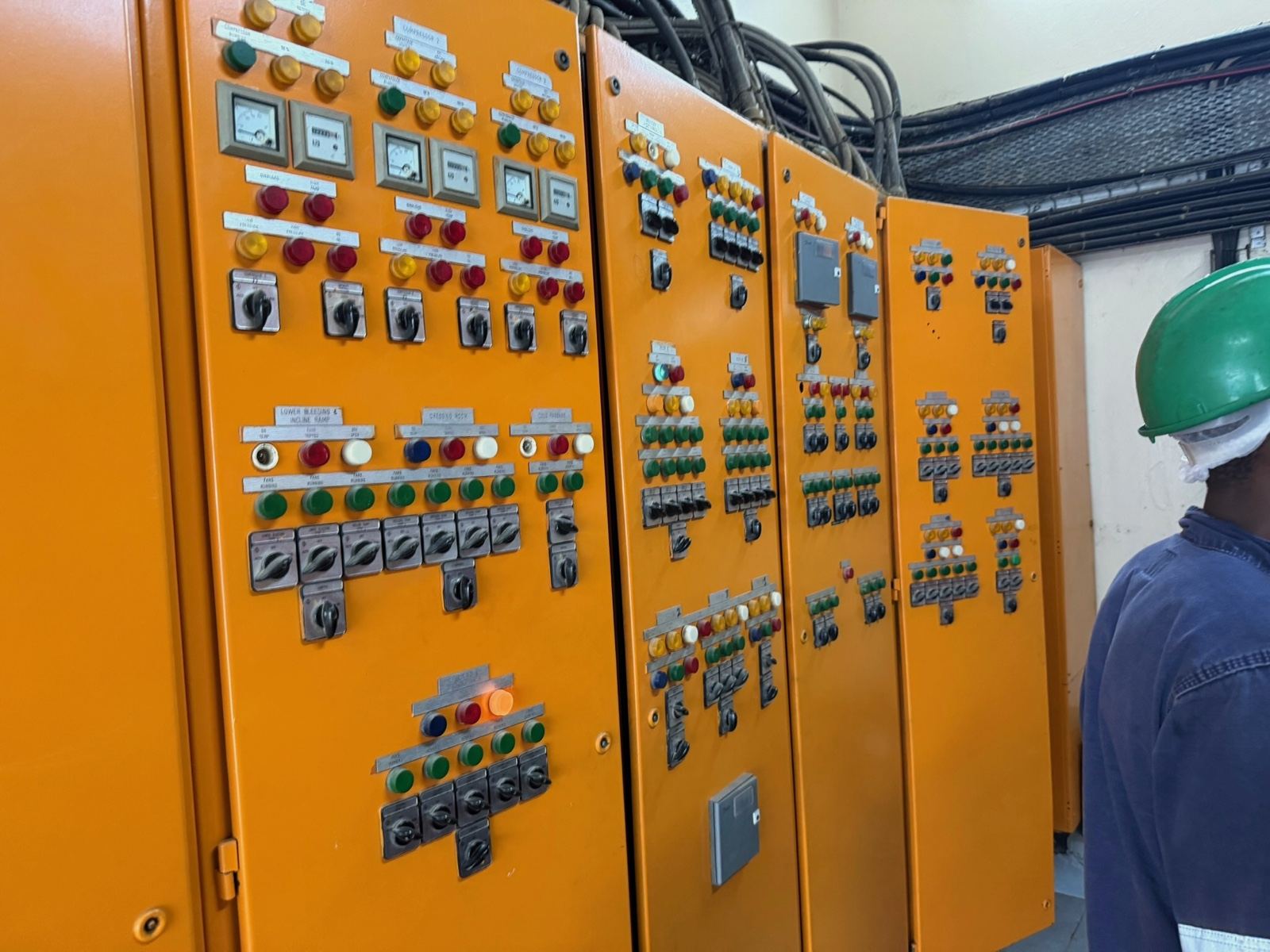 A long run of orange control panels with rows of switches and indicator lights