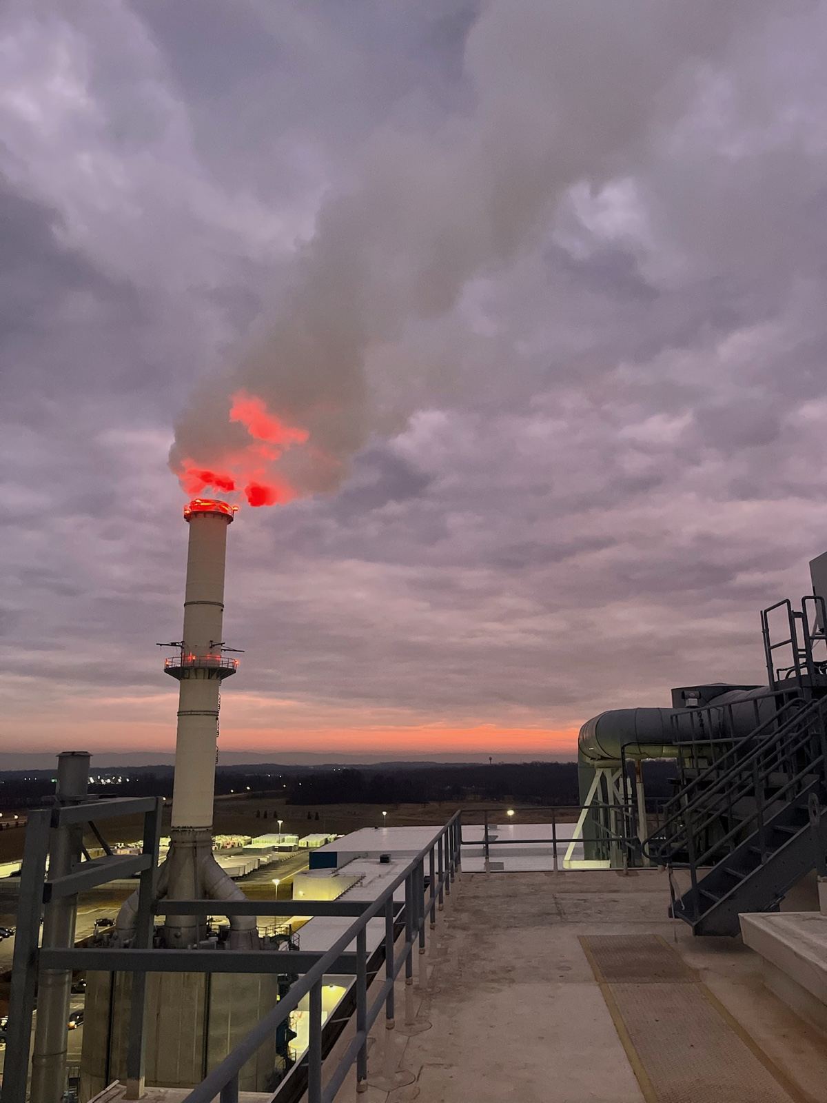 An insulation plant’s stack burning off at dusk under a purple sky